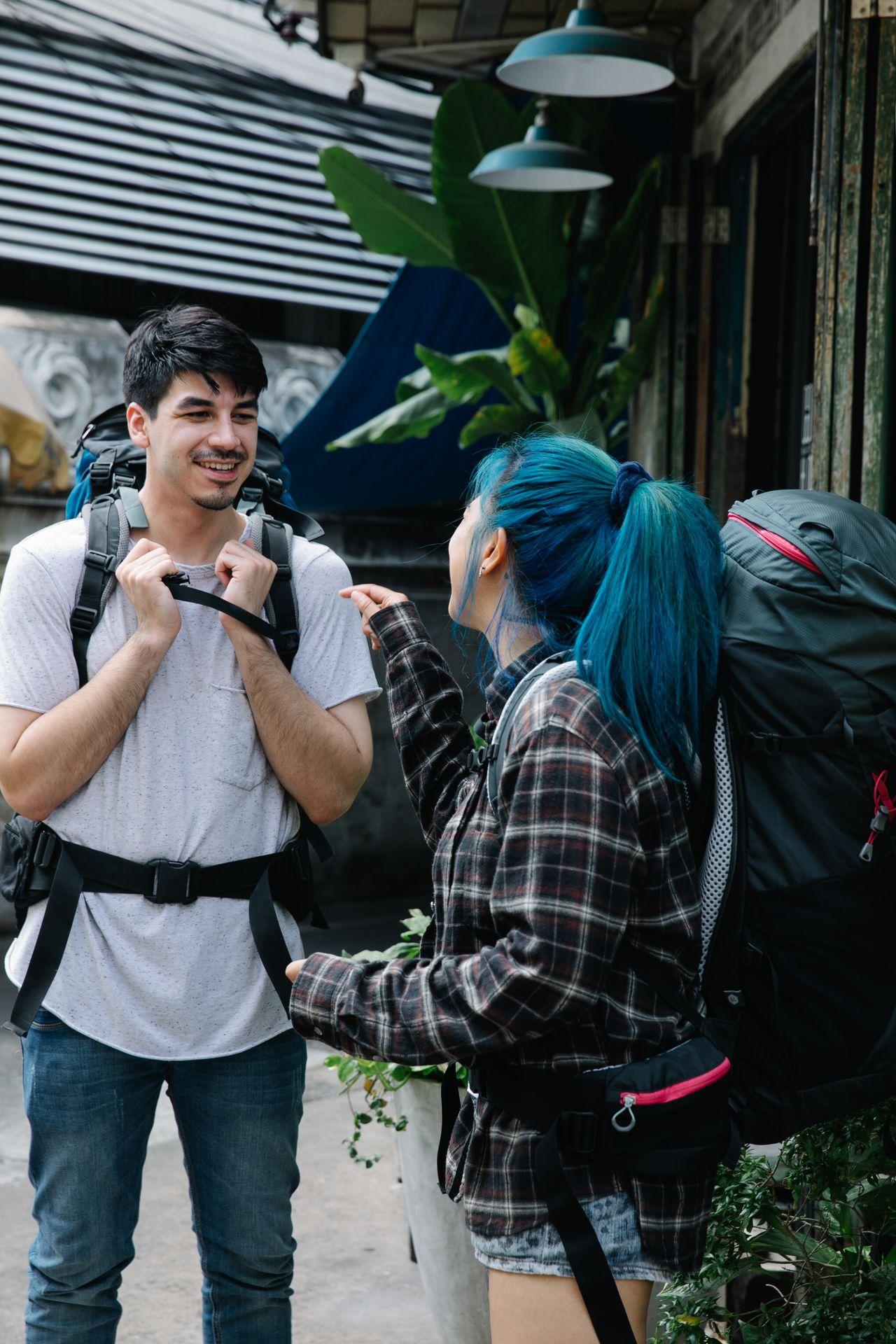 Two friends with travel bags greet each other outside a station